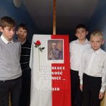 Czterech chłopców stoi obok dekoracji z okazji Dnia Niepodległości. Na sztaludze biało - czerwona flaga, zdjęcie Piłsudskiego, napis: Dał Polsce wolność i granice, data: 11. 11. 1918