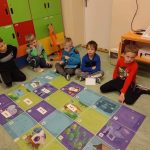 Pięcioro dzieci siedzi w sali lekcyjnej przed matą Photona