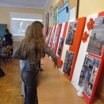 Dziewczęta w sali lekcyjnej oglądają dekorcję na temat Powstania Warszawskiego