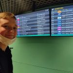 Uśmiechnięty chłopiec przed tablicą przylotów i odlotów