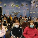 Grupa uczniów zwiedzających lotnisko siedzi w sali słuchając wykładu