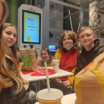 Trzy dziewczynki i jeden chłopiec siedzą przy stoliku w restauracji