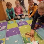 Grupa dzieci patrzy na spacerującego po macie robota