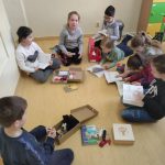 Pięć dziewczynek i trzech chłopców siedzi na podłodze i czyta książki.