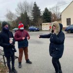 Dwaj chłopcy zbierający datki na Wielką Orkiestrę Świątecznej Pomocy. Przed nimi kobieta wrzucająca do puszki datek