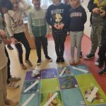 Grupa uczniów przy macie. Na niej Photon oraz kartki ćwiczeniowe.