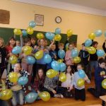 24 dzieci trzyma w rękach żółte i niebieskie balony na znak solidarności z Ukrainą.