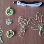 Ułożone na ławce kształty: dwa liście, emotikony i kot, wykonane długopisem 3D