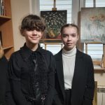 Trzy uczennice na tle obrazów, których tematem są kwiaty.