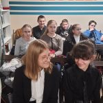 Kilkoro uczniów siedzących na krześle w bibliotecznej czytelni.