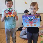 Chłopcy prezentują motyla zbudowanego z klocków edukacyjnych.