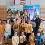 Uczniowie klas drugich stoją na tle sceny z kukiełkami.