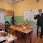 Modele urządzeń zbudowane z kolorowych klocków ustawione na ławce w sali lekcyjnej. Obok nauczyciel prowadzący lekcję.