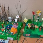 Na stoliku wystawa prac przesrzennych: drzewa, kwiaty, bociany, motyle