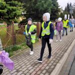 Uczniowie zbierają śmieci wkoło szkoły.