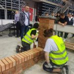 Dwóch mężczyzn buduje ogrodzenie z cegieł