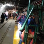 Dzieci w kolorowych ubraniach siedzące na kolejce w kopalni.