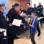 Chłopiec odbiera nagrodę piłkę od policjanta
