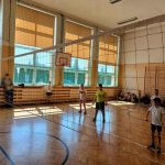 Czworo uczniów na boisku do siatkówki czeka na rozegranie piłki przez drużynę przeciwną