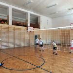 Chłopiec serwuje, przeciwnicy są w postawie gotowej do przyjęcia piłki