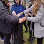 Czworo dzieci. Jedna osoba trzyma czarny worek pozostałe wrzucają zebrane śmieci