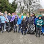 Wszyscy uczniowie stoją w zwartej grupie z zebranymi dwoma workami śmieci
