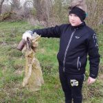 Chłopiec trzymający znaleziony żółty worek oraz butelkę