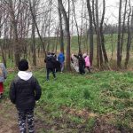 Grupa dzieci między drzewami zbiera śmieci