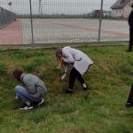 Dwie pochylone dziewczynki zbierają śmieci z pobocza drogi