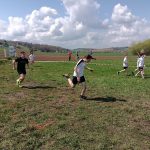 Wyścig chłopców, na pierwszym planie biegnie chłopiec w białym podkoszulku, za nim chłopiec w czarnym podkoszulku