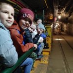 Pięcioro uśmiechniętych dzieci siedzących na kolejce w kopalni.