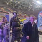 Nauczyciel na tle stoiska wystawowego.