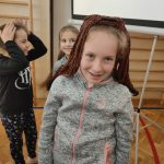 dziewczynka w szaro-różowej bluzie z peruką na głowie.