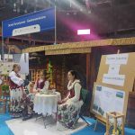 Dwie dziewczyny w strojach ludowych siedzą przy okrągłym stoliku