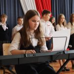 Dziewczynka podczas gry na keyboardzie, w tle pozostali występujący