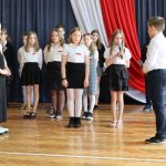 Czworo uczniów recytuje wiersze, za nimi pozostali występujący.