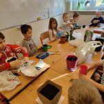 Uczniowie umieszczają swoje rośliny w doniczkach z ziemią.