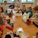 Uczniowie wsypują ziemię do doniczek.