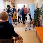 Uczniowie szukają ukrytych pisanek na korytarzu.