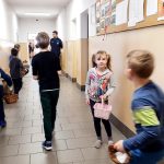 Uczniowie z koszykami zbierają ukryte pisanki.