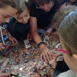 Kilkoro uczniów pochyla się nad tablicą wyklejoną kilkoma setkami zdjęć głów kobiet i mężczyzn w poszukiwaniu podobizny Stanisława Miłkowskiego