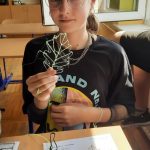 Chłopiec ubrany w granatowy dres trzyma w ręku pióro, które zostało wykonane długopisem 3d.