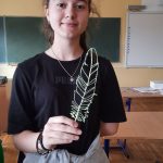 uczennica ubrana w granatową bluzę z kolorowymi elementami, która trzyma liść wykonany techniką 3d.