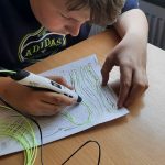 Chłopiec za pomocą długopisu 3D obrysowuje kształty rysunku