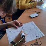 Dziewczynka pochylona nad pracą, wykonuje długopisem rysunek.