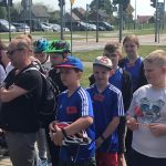 Grupa uczniów stojąca obok siebie, za nimi miasteczko ruchu drogowego ze znakami i światłami.