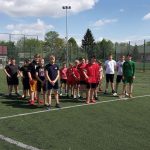 Pani dyrektor w ciemnych okularach i chłopiec w białej koszulce i zielonych spodenkach prezentuje puchar i dyplom.