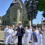 Dzieci komunijne słuchają katechety. W tle sanktuarium.