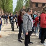 Grupa osób stoi przy murze więziennym