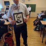 Chłopiec w białek koszuli z muszką w czerwone grochy i w ciemnych spodniach, trzyma w rękach kartkę z podobizną Stanisława Miłkowskiego